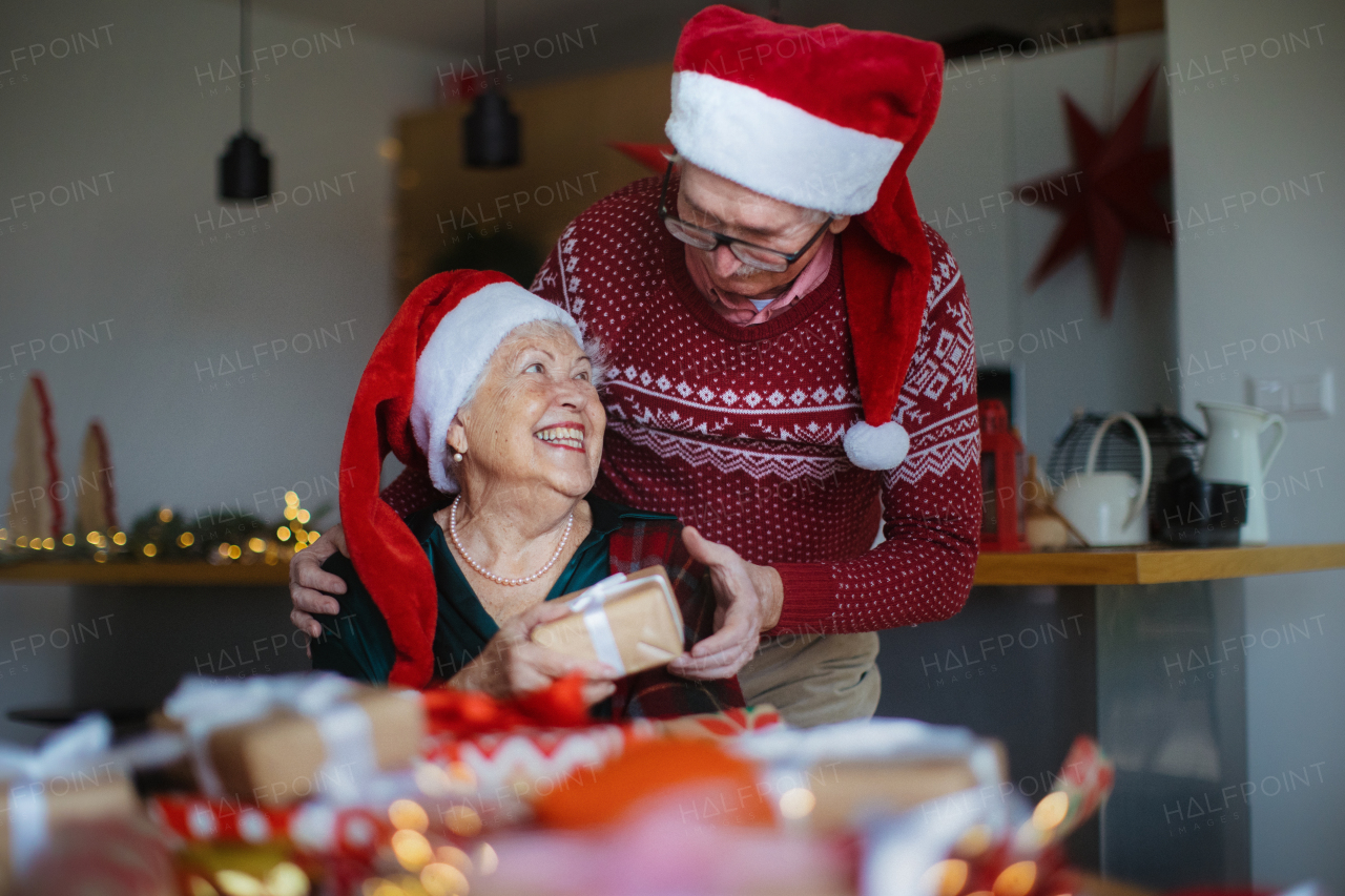 Senior couple celebrating Christmas, giving the gifts each other.