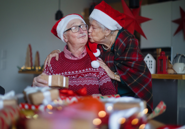 Senior couple celebrating Christmas, giving the gifts each other.