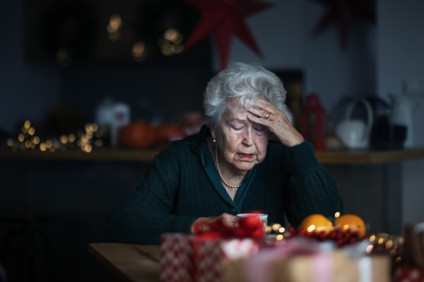 Unhappy senior woman sitting alone and crying during Christmas Eve. Concept of solitude seniors.