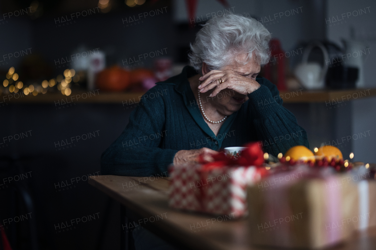 Unhappy senior woman sitting alone and crying during Christmas Eve. Concept of solitude seniors.