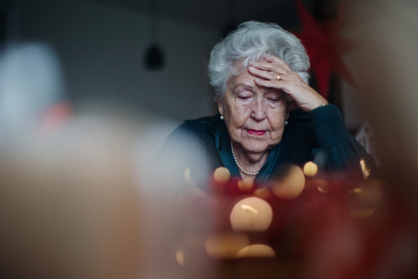 Unhappy senior woman sitting alone and crying during Christmas Eve. Concept of solitude seniors.