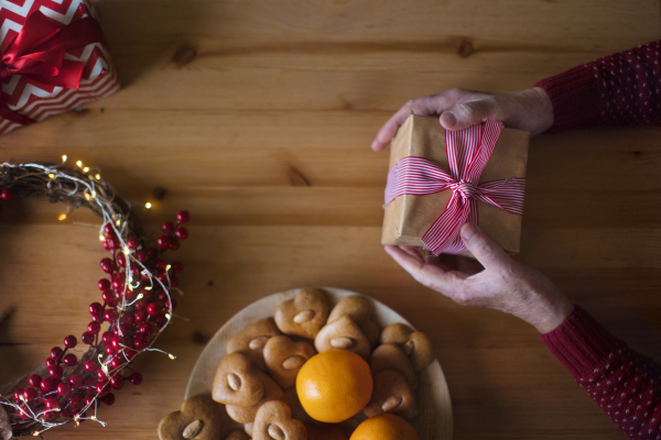 Top view of Christmas decorations and man holding Christmas gift above table. Copy space.