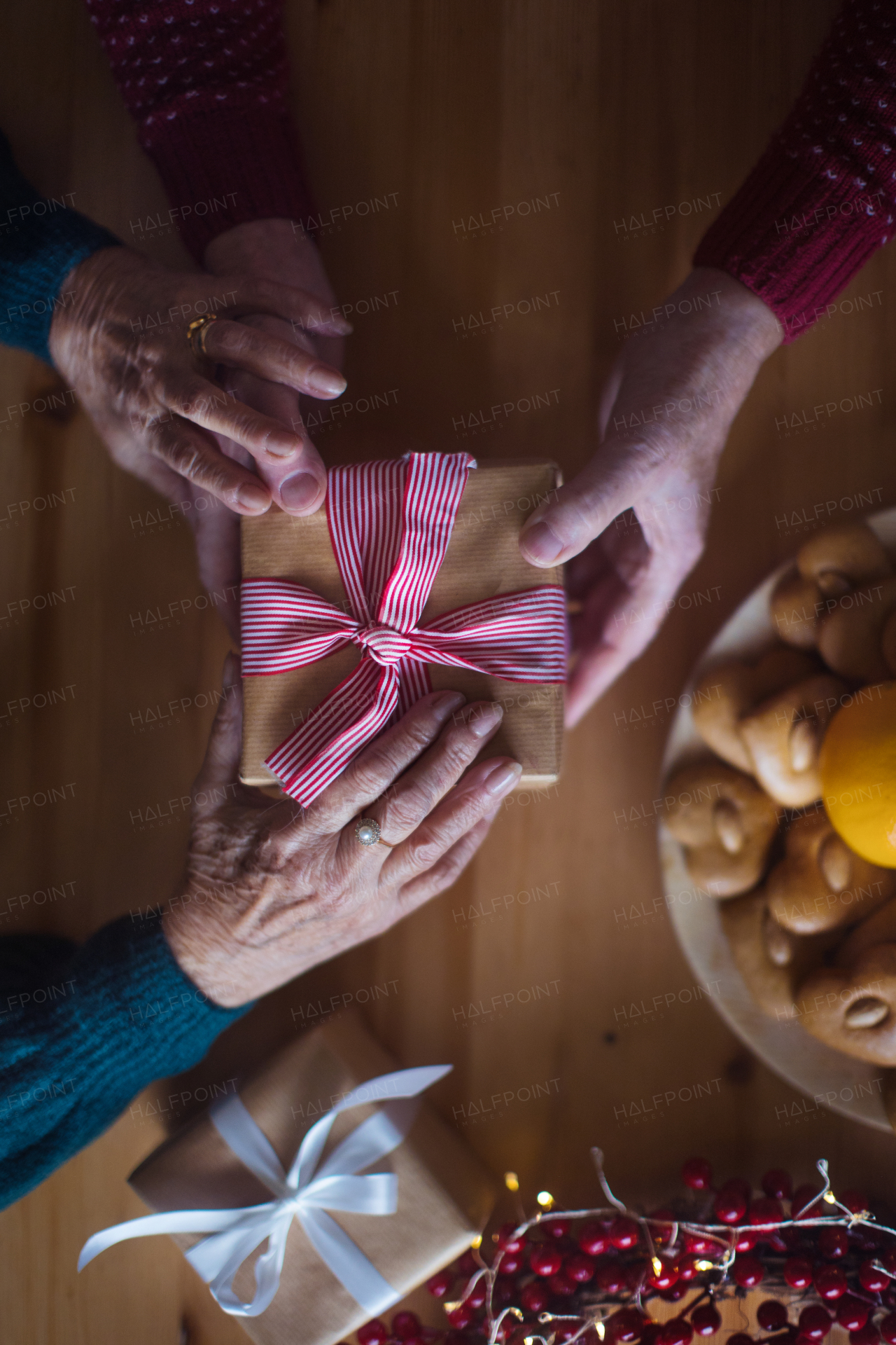 Top view of Christmas table with decorations and hands giving gifts. Copy space.