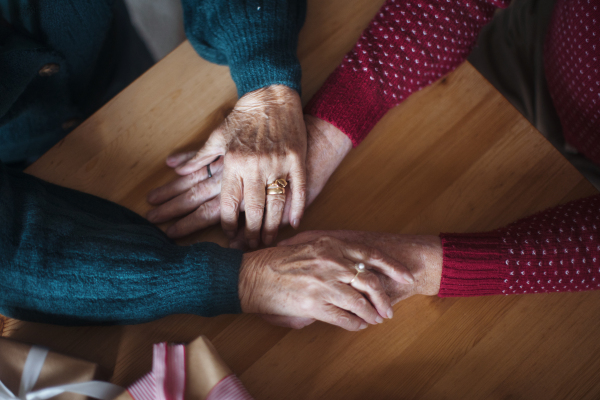 Top view of seniors couple hands holding each other, during Christmas Eve.