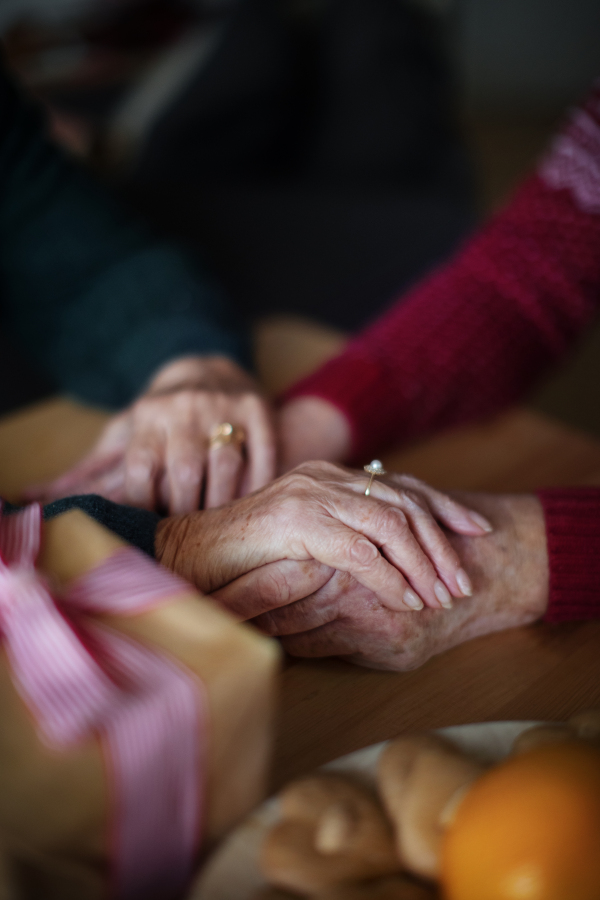 High angle view of seniors couple hands holding each other, during Christmas Eve.