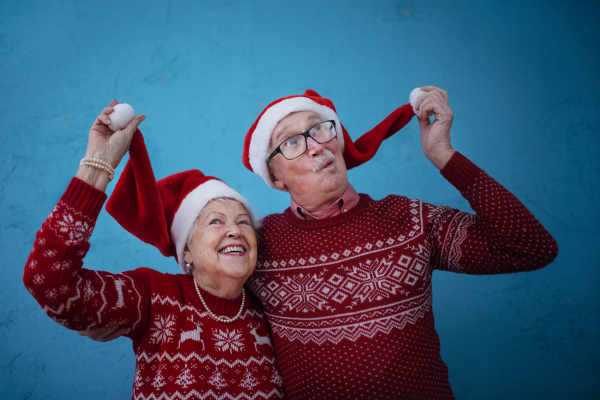 Portrait of happy senior couple, in front of blue background.