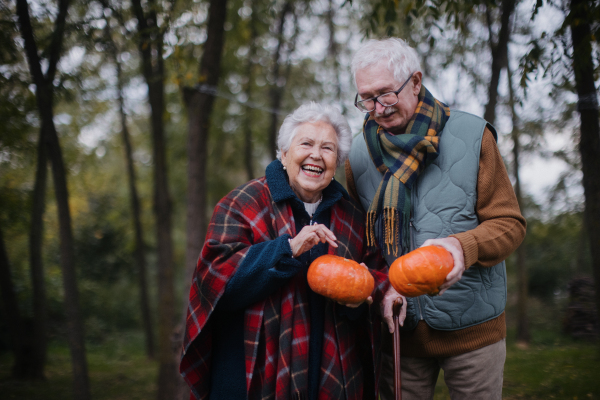 Senior couple with pumpkins in autumn nature.