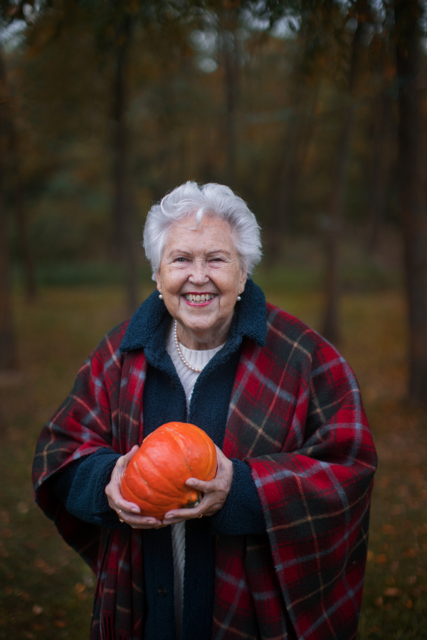 Senior woman with pumpkins in autumn nature.