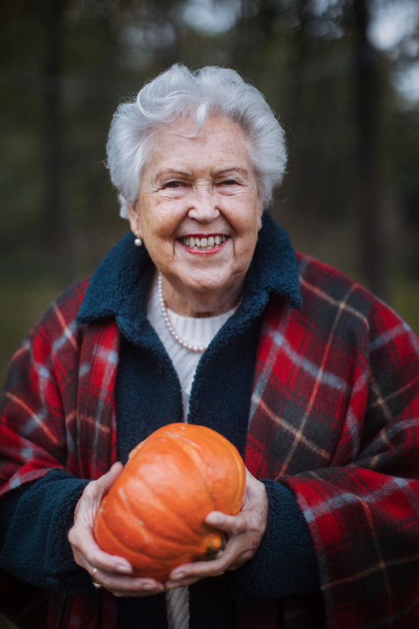 Senior woman with pumpkins in autumn nature.