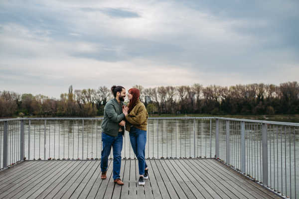 Beautiful couple on romantic date in the city, walking along the boardwalk by the river. Together during cold spring, autumn day.