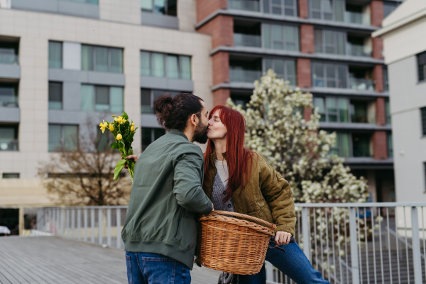 Girlfriend and boyfriend meeting in the city, greeting each other with hug and kiss. Romantic date during cold spring day.