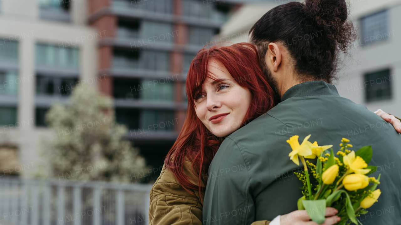 Girlfriend and boyfriend meeting in the city, greeting each other with hug. Romantic date during cold spring day.