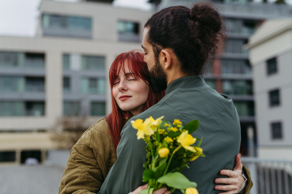 Girlfriend and boyfriend meeting in the city, greeting each other with hug. Romantic date during cold spring day