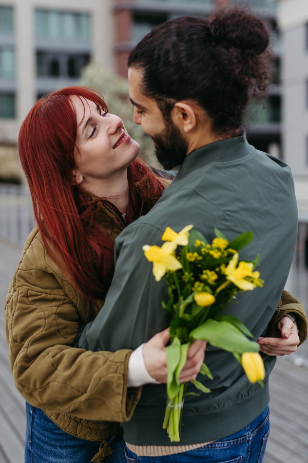 Girlfriend and boyfriend meeting in the city, greeting each other with hug and kiss. Romantic date during cold spring day.