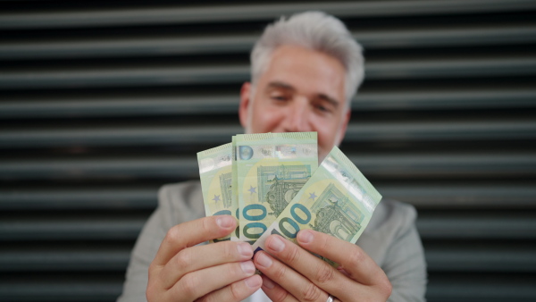 Man standing in a street and showing money at camera.