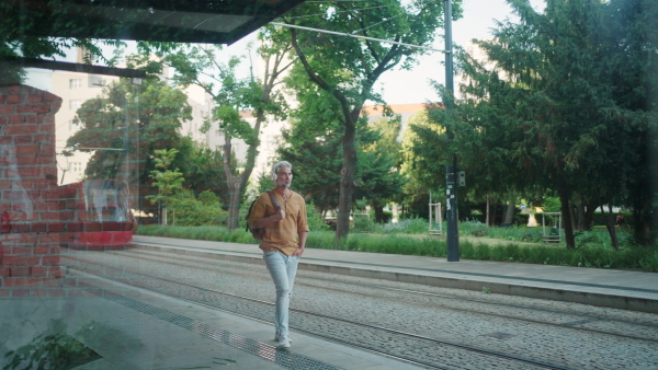 Commuter man walking on street and listening music by headphones.