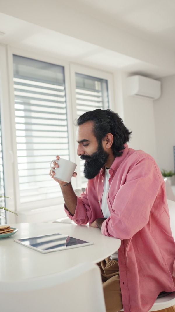 A man adjusting household functions, lighting, security cameras, door locks and thermostat or heating settings in the smart home system. Vertical view.