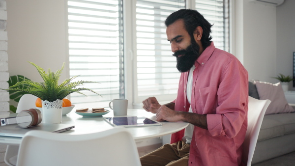 A man adjusting household functions, lighting, security cameras, door locks and thermostat or heating settings in the smart home system.