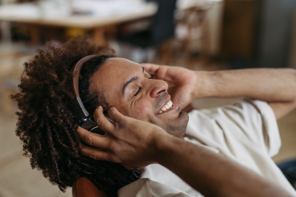 Portrait of young multiracial man listening music in an office.