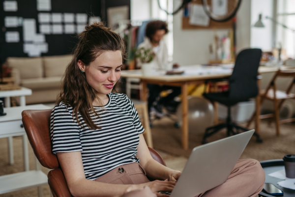 Young woman working on laptop in creative atelier.