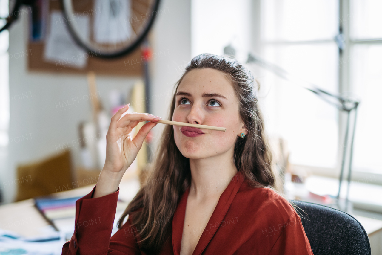 Portrait of a funny woman with pencil in mouth, having fun at work.