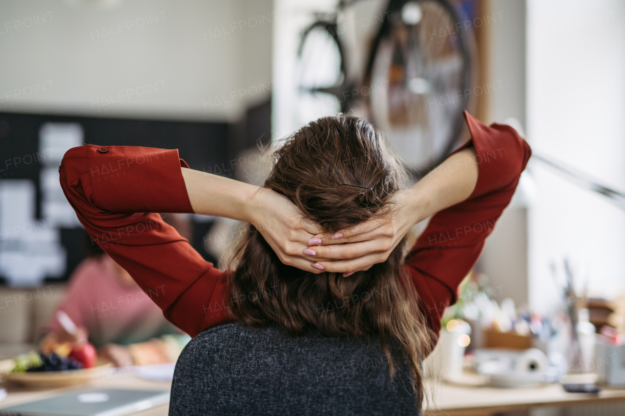 Rear view of young woman stretching in a work, having break.