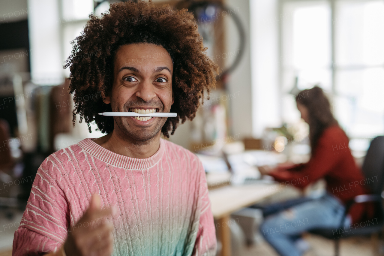 Portrait of a funny man with pen in mouth, having fun at work.