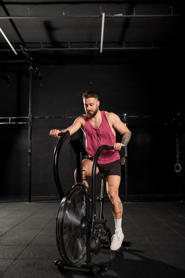 Man exercising on elliptical cross-trainer machine, wearing an activewear. Routine workout for physical and mental health.