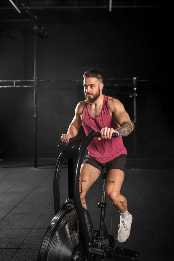 Man exercising on elliptical cross-trainer machine, wearing an activewear. Routine workout for physical and mental health.