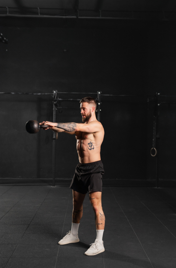 Man performing kettlebell swings, holding kettlebell in both hands. Strength exercise. Routine workout for physical and mental health.