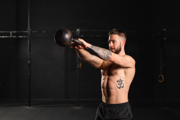 Man performing kettlebell swings, holding kettlebell in both hands. Strength exercise. Routine workout for physical and mental health.