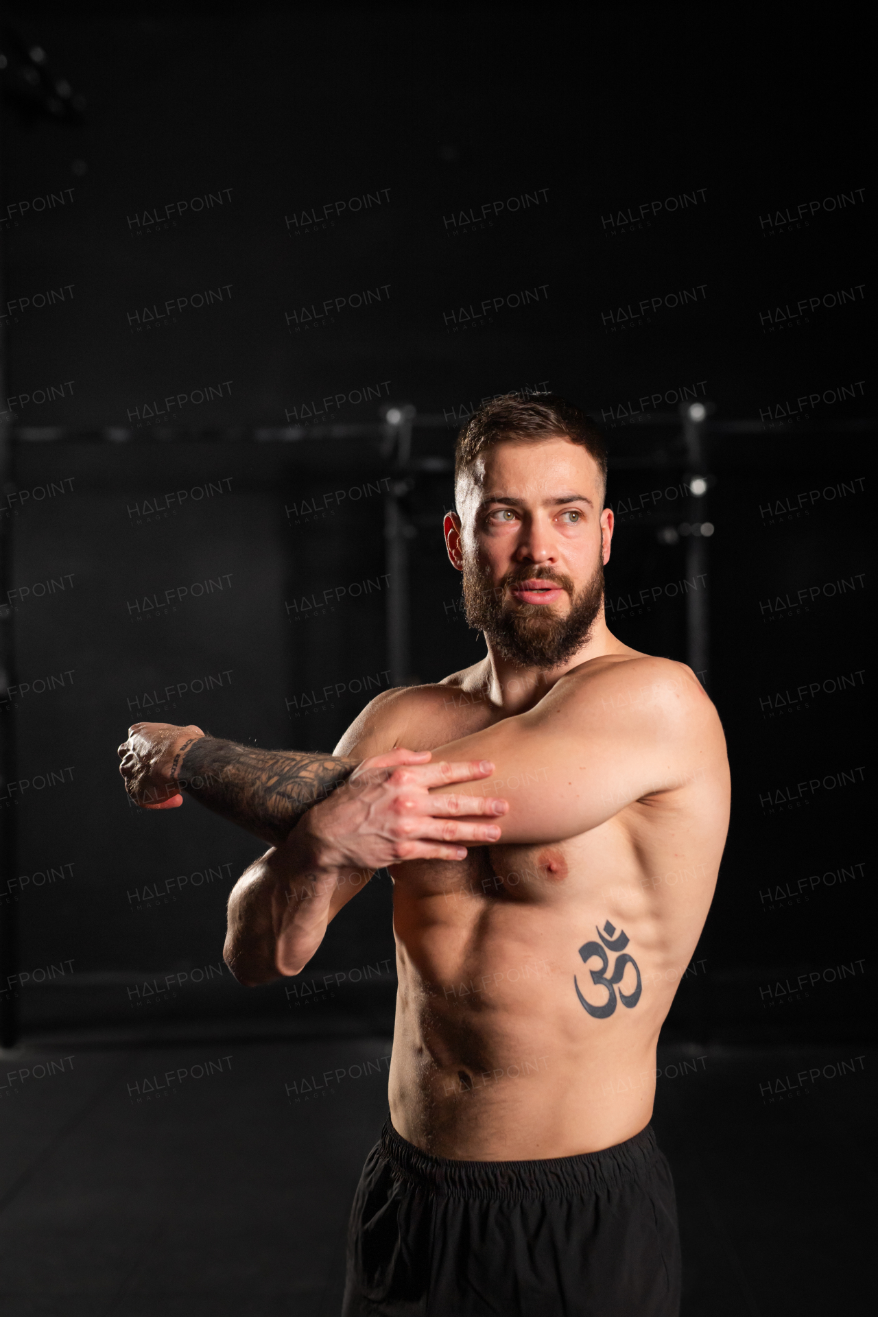 Portrait of handsome muscular man stretching before training in the gym, standing. Routine workout for physical and mental health.