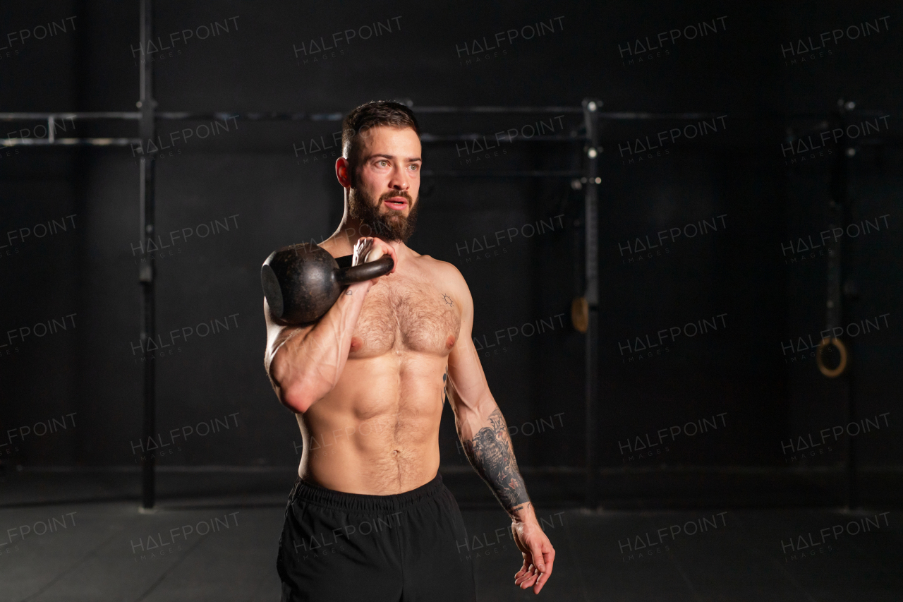 Man lifting a weight with hand, one arm dumbbell snatch, wearing only shorts, bare chest. Routine workout for physical and mental health.