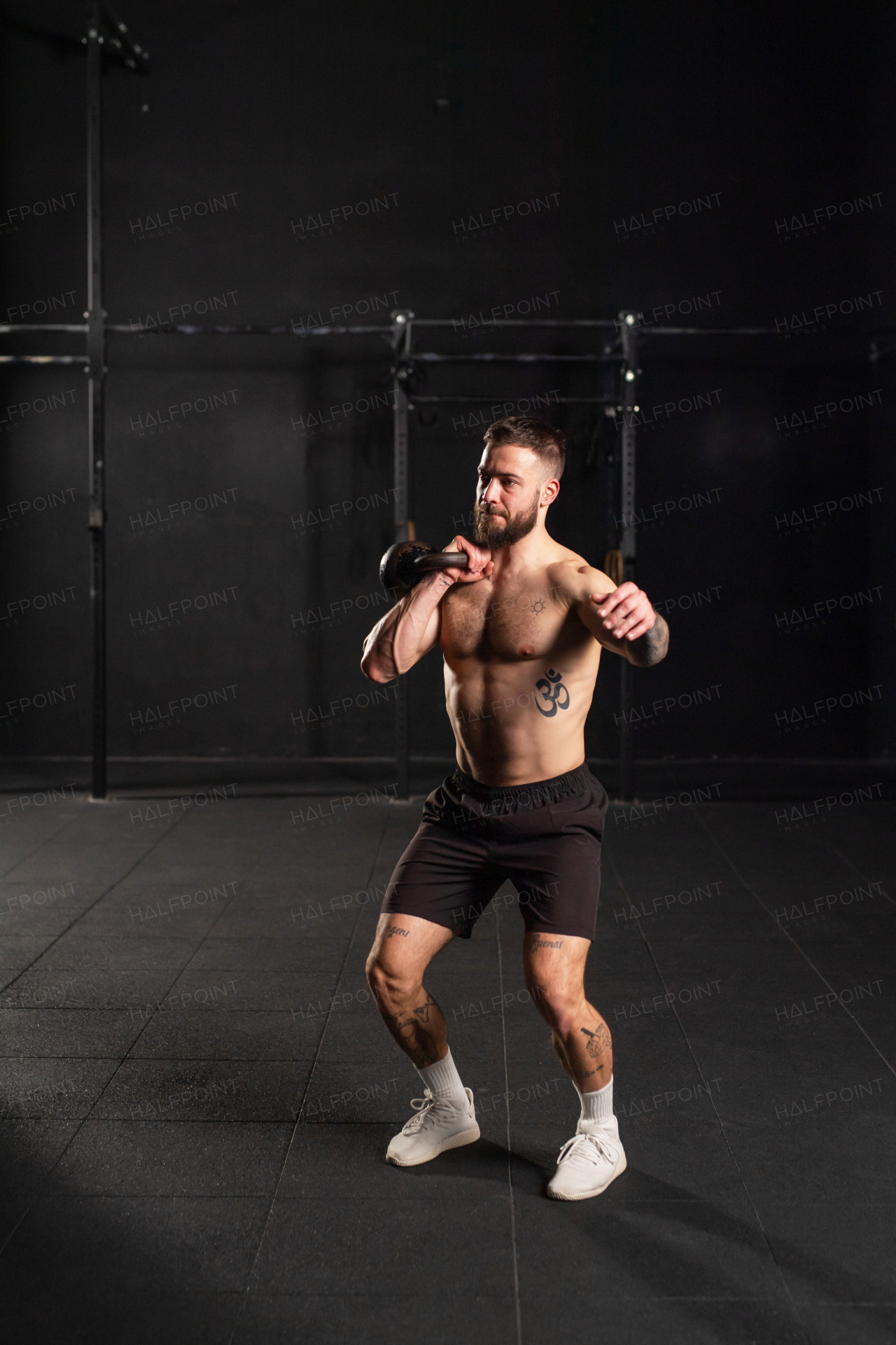 Man lifting a weight with hand, one arm dumbbell snatch, wearing only shorts, bare chest. Routine workout for physical and mental health.