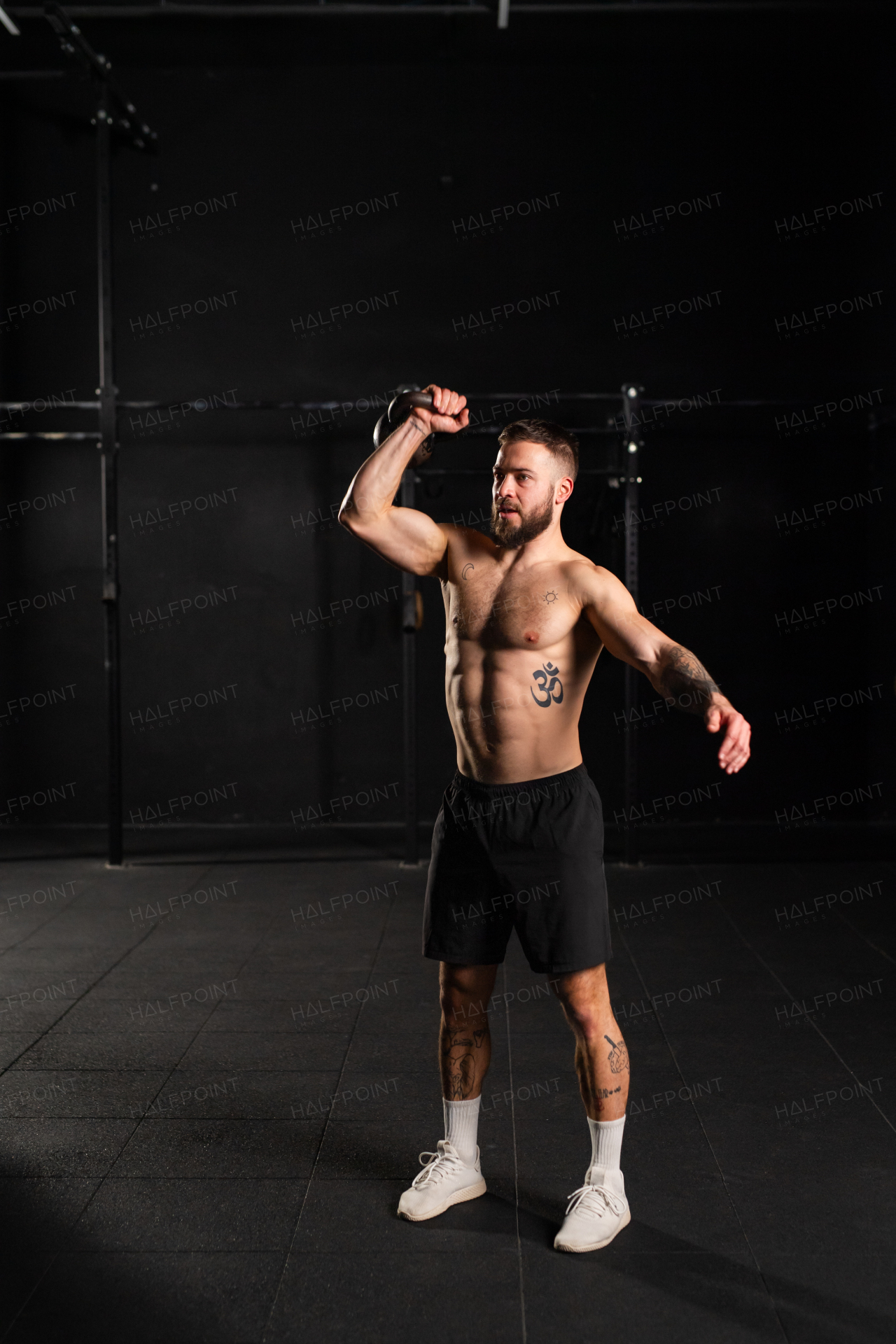 Man lifting a weight with hand, one arm dumbbell snatch, wearing only shorts, bare chest. Routine workout for physical and mental health.