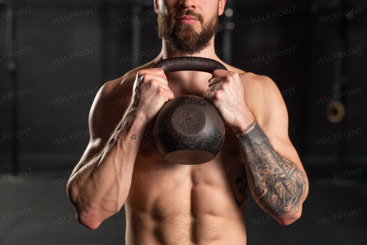 Close up of man holding dumbbell in front his muscular bare chest. Routine workout for physical and mental health.