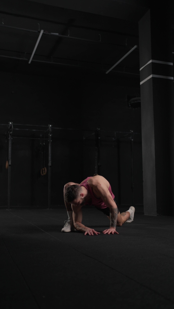 Video of handsome muscular man stretching his body, squatting, in gym. Routine workout for physical and mental health.