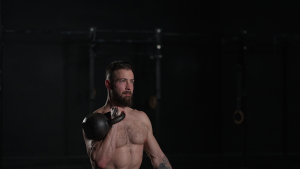 Man lifting dumbbellr, wearing only shorts, bare chest. Routine workout for physical and mental health.