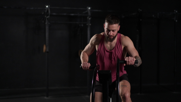 Man exercising on elliptical cross-trainer machine, wearing an activewear. Routine workout for physical and mental health.