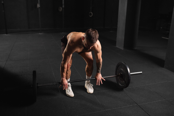 Strong man performing deadlift, lifting barbell from ground., full length shot. Routine workout for physical and mental health.