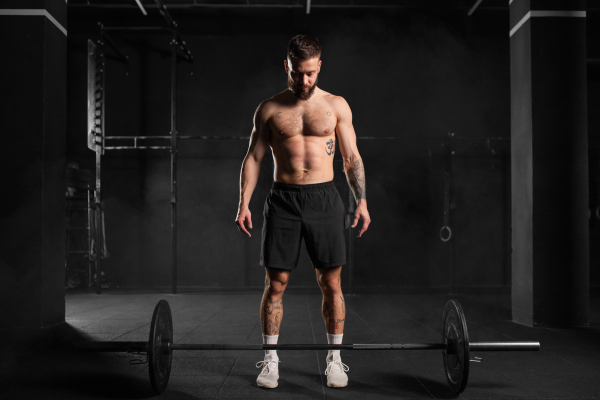 Strong man preparing for a barbell lift, overhead squat, standing by barbell. Routine workout for physical and mental health.