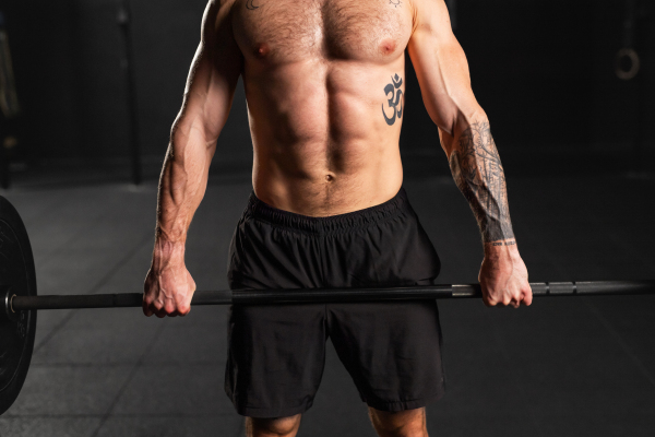 Strong man preparing for a barbell lift, overhead squat, standing by barbell. Routine workout for physical and mental health.