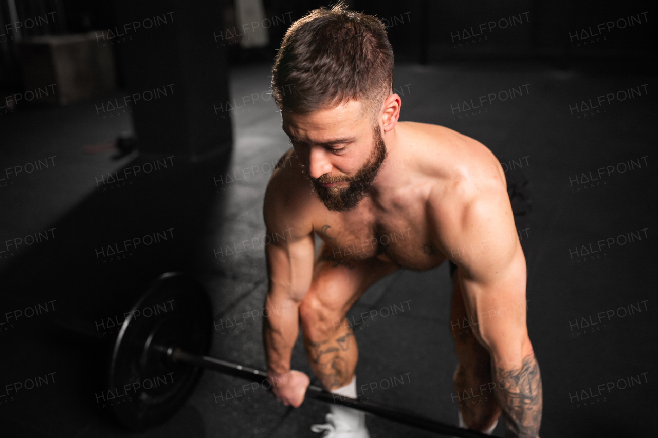 Strong man performing deadlift, lifting barbell from ground, full length shot. Strength exercise. Routine workout for physical and mental health.