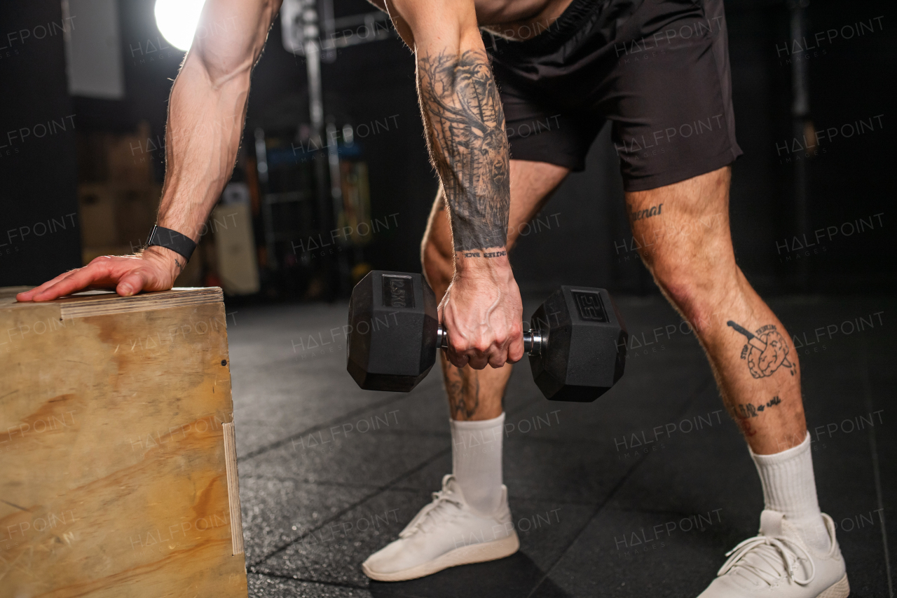 Close up of man performing single arm dumbbell row in bent-over position. Strength exercise. Routine workout for physical and mental health.