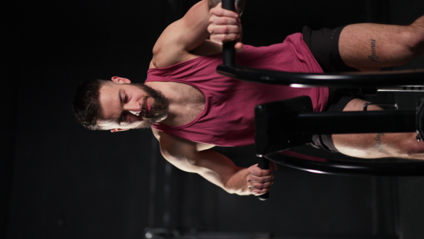 Vertical view of a man exercising on elliptical cross-trainer machine, wearing activewear. Routine workout for physical and mental health. Vertical view.