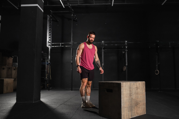 Portrait of handsome muscular man in gym, wearing workout clothes. Routine workout for physical and mental health.