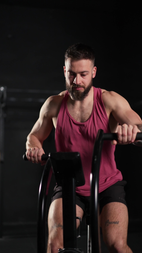 Man exercising on elliptical cross-trainer machine, wearing an activewear. Routine workout for physical and mental health.