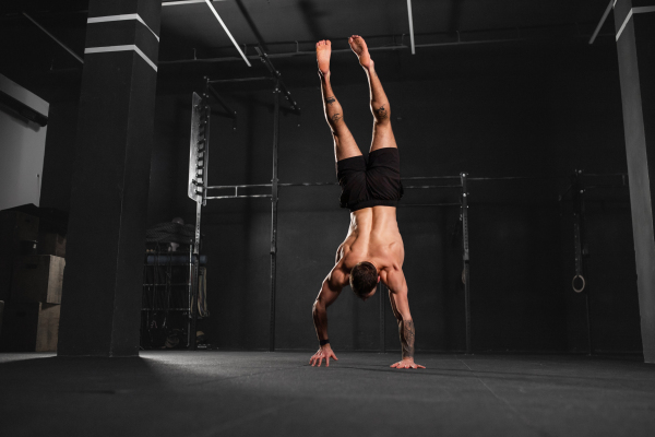 Rear view of handstand exercise, handstand push-ups by strong man. Vertical box jumps workout. Routine workout for physical and mental health.