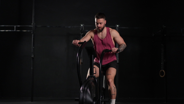 Man exercising on elliptical cross-trainer machine, wearing an activewear. Routine workout for physical and mental health.