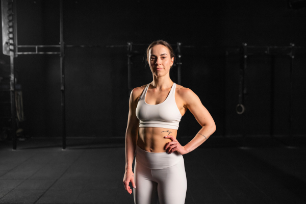 Portrait of young muscular woman in gym, wearing sportswear. Routine workout for physical and mental health.